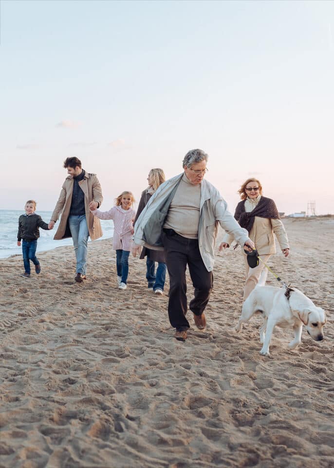 Family walking on beach together with dog in California